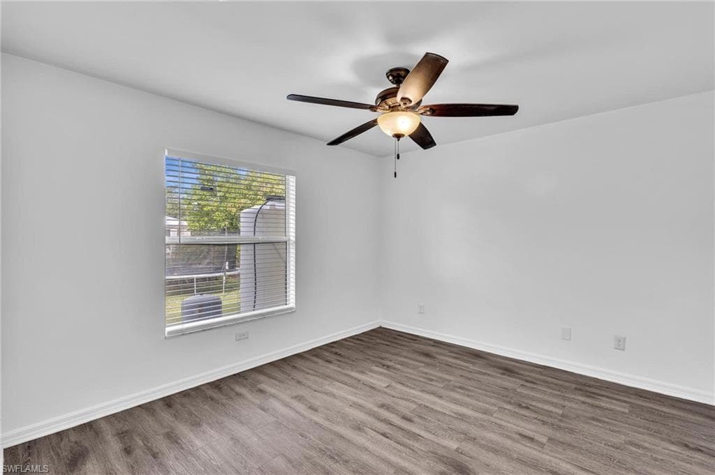 Room featuring wood-finish flooring and a ceiling fan with integrated lighting