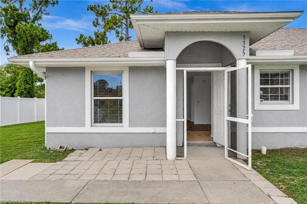 Stucco exterior featuring an arched portico entry with dual columns