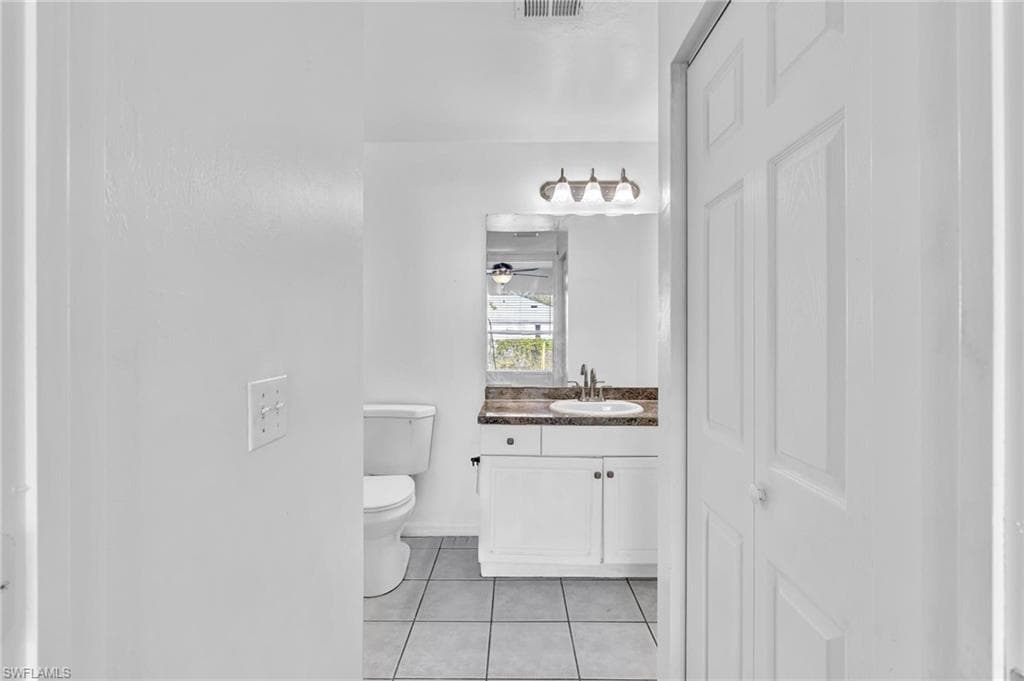 Bathroom featuring a white vanity with two-door cabinetry, a dark countertop, and a rectangular sink with a chrome faucet