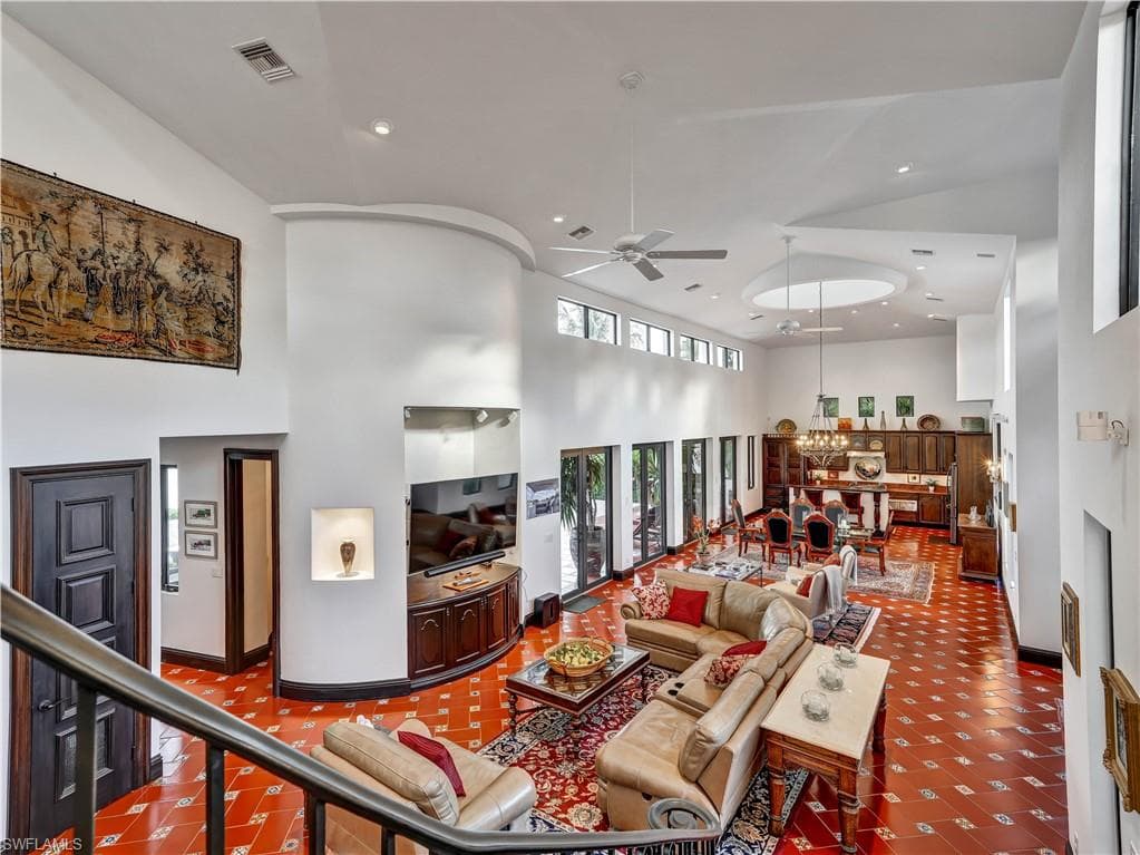 Expansive living area with high ceilings, recessed lighting, and patterned terra cotta flooring