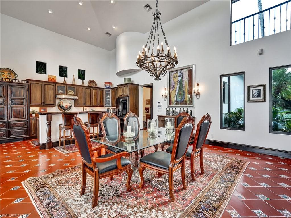 High ceilings featuring an ornate chandelier, dark wood cabinetry, a built-in bar, and high transom windows