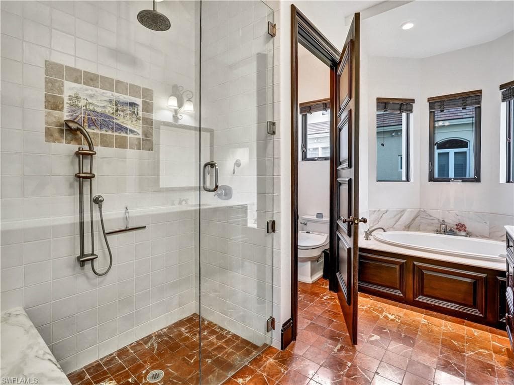 Bathroom featuring a spacious walk-in shower with clear glass enclosure, overhead rainfall showerhead, and a handheld shower fixture