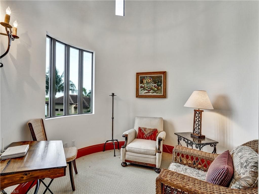 Curved window with multiple vertical panes, white walls, and a red baseboard