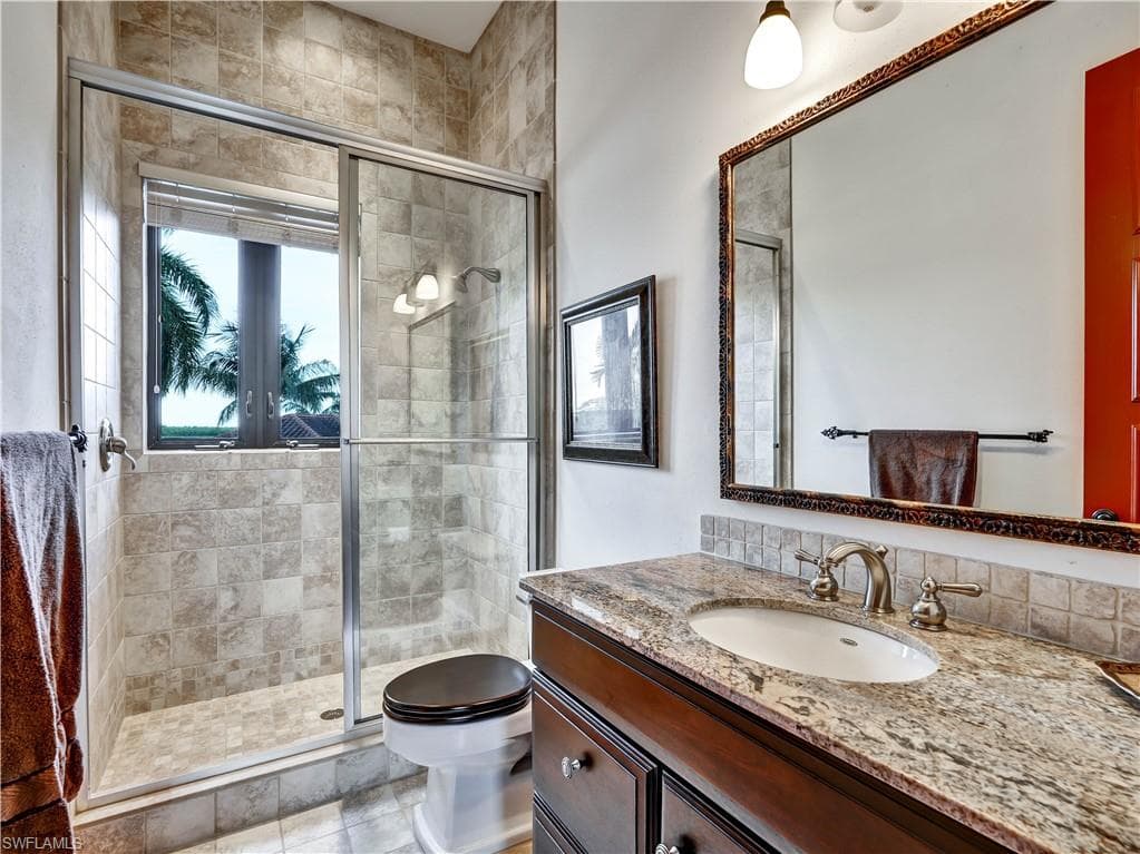Walk-in shower with glass enclosure and light-toned tile surround