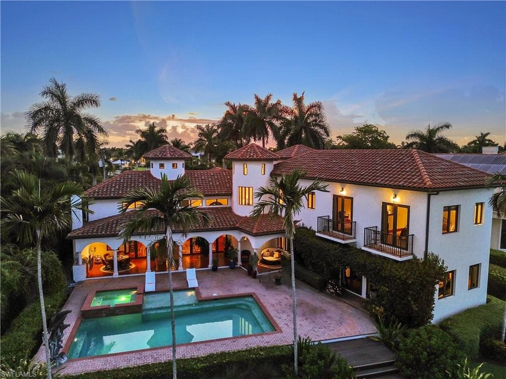 Mediterranean-inspired residence featuring a terracotta tile roof and white stucco exterior
