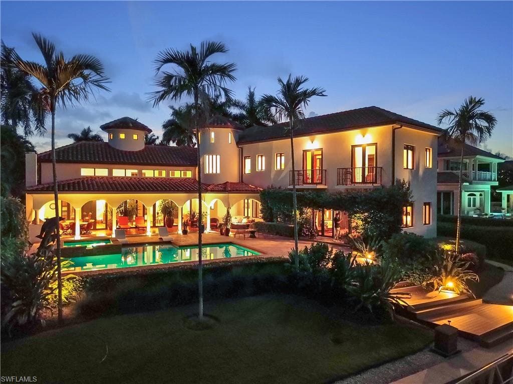 Mediterranean-style residence featuring a tile roof, stucco exterior, multiple balconies, and a private dock