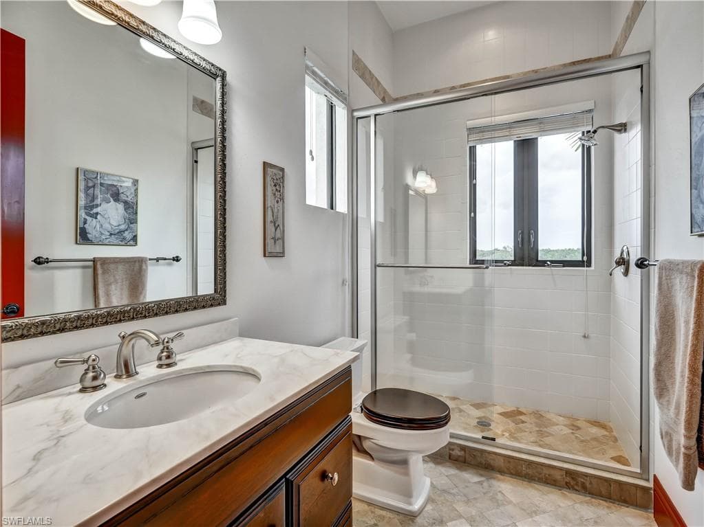 Bathroom featuring a rich wood-tone vanity with a marble-finish countertop, undermount sink, and brushed nickel fixtures