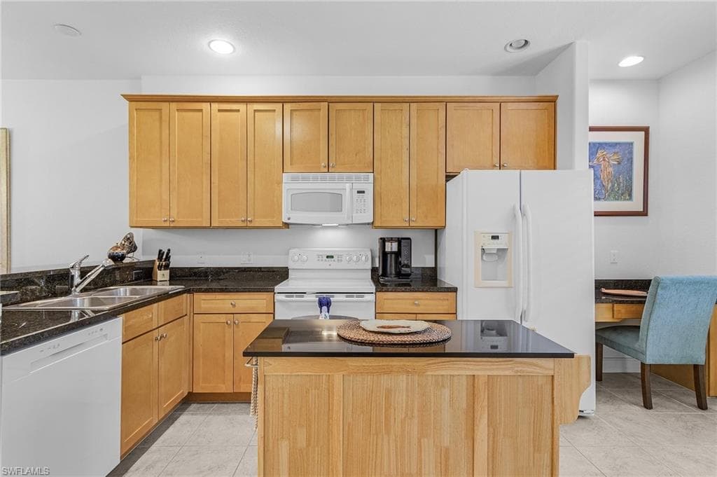 Kitchen with white appliances, a sink, light tile patterned flooring, a center island, and recessed lighting