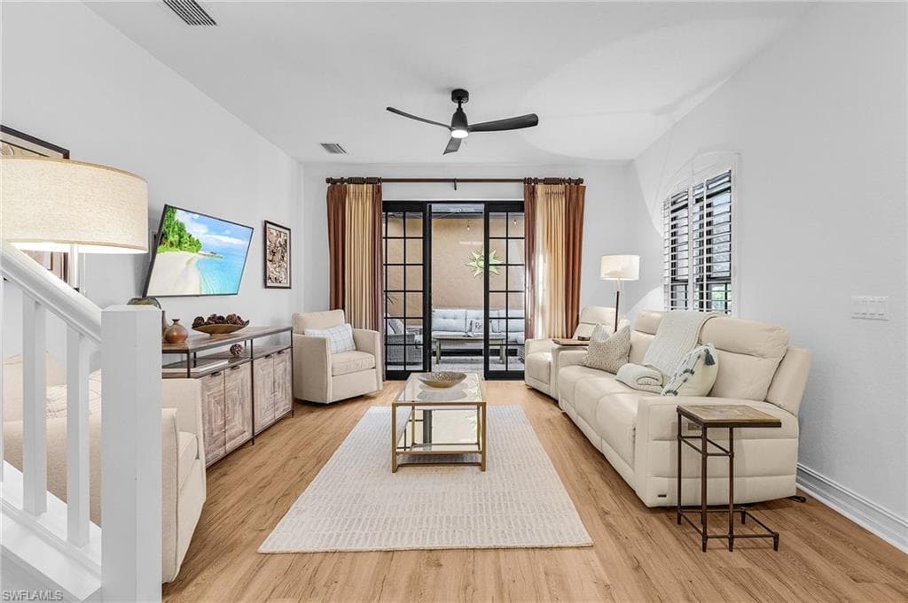 Living area featuring stairs, wood finished floors, a ceiling fan, and baseboards