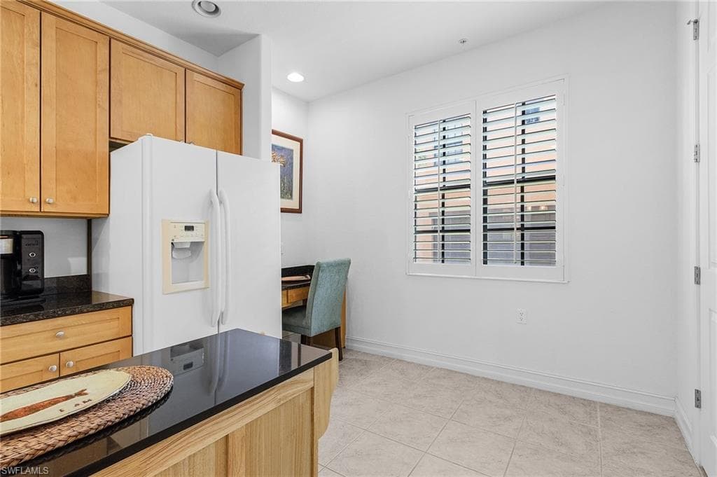 Kitchen featuring white fridge with ice dispenser, baseboards, recessed lighting, and light tile patterned floors