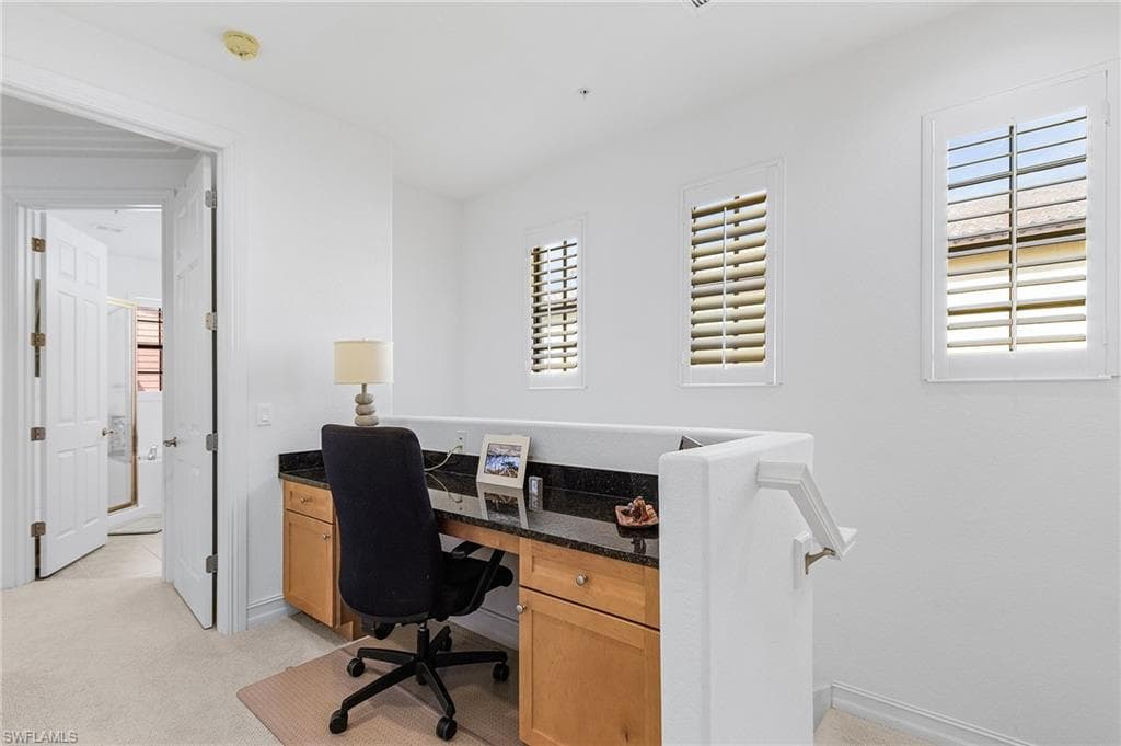 Office area featuring light colored carpet and baseboards