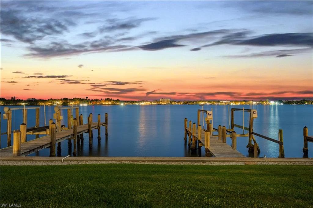 Dock area with boat lift, a yard, and a water view