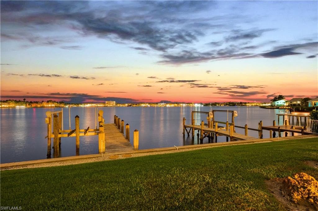 Dock featuring a lawn, boat lift, and a water view