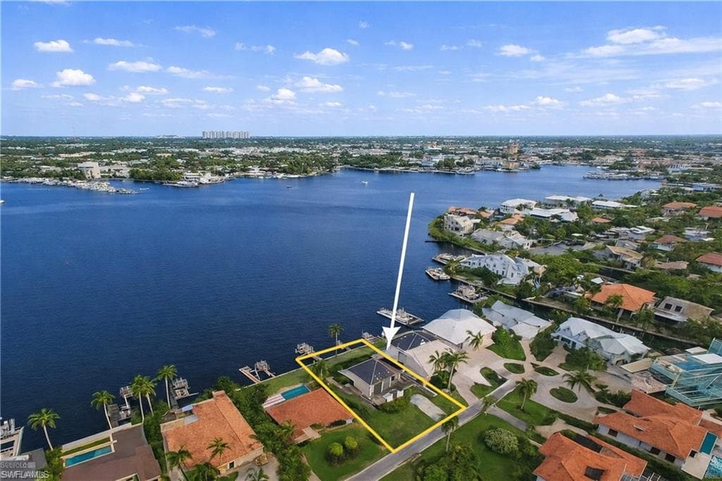 Aerial perspective of suburban area with property parcel outlined and a large body of water