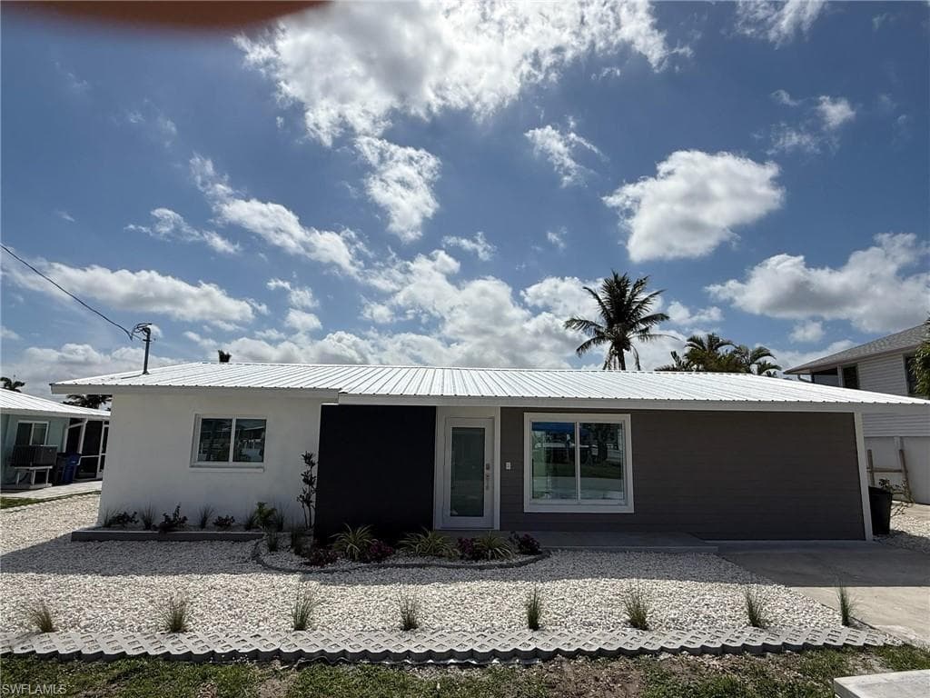 Ranch-style home with metal roof and stucco siding