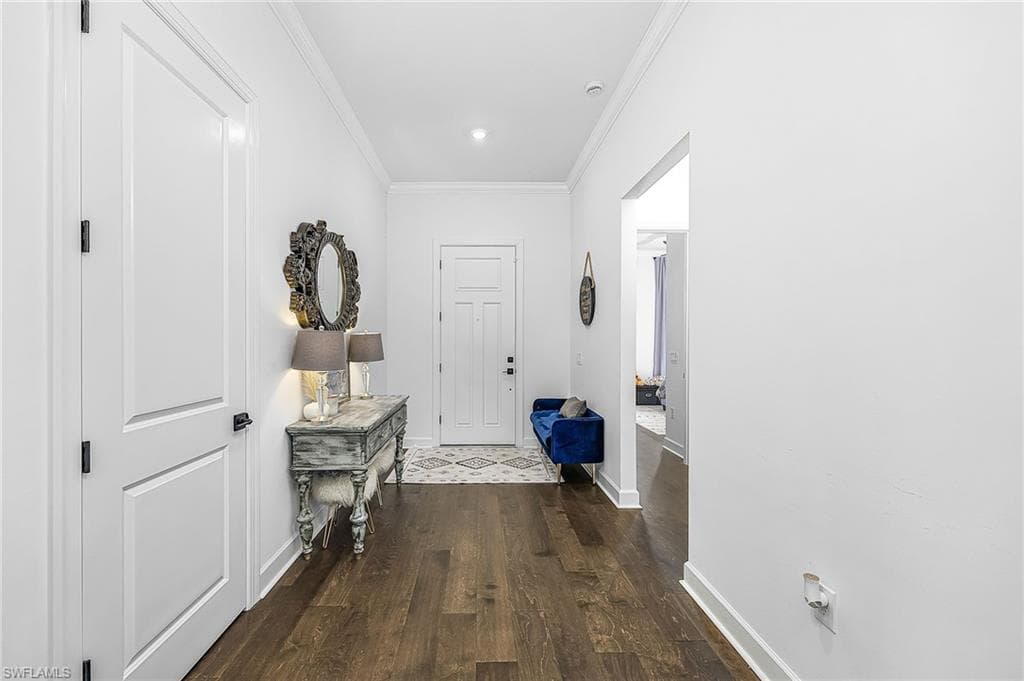 Corridor with crown molding and dark wood-type flooring
