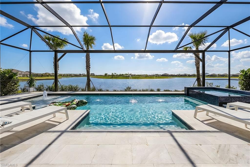 Combined pool / hot tub featuring a water view, a sunroom, and glass enclosure