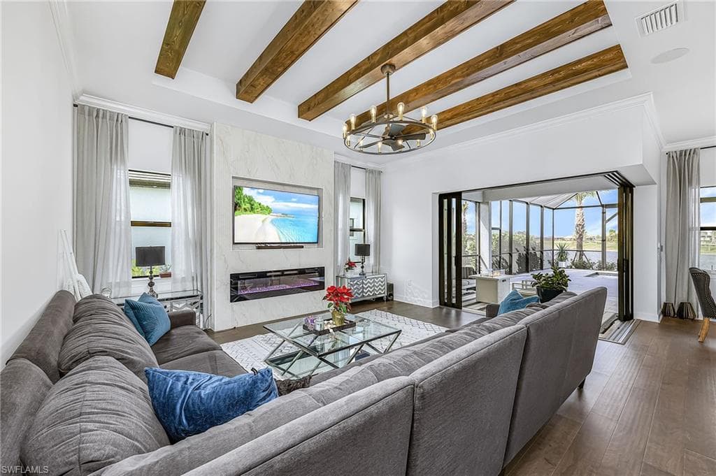 Living area featuring beam ceiling, a premium fireplace, a sunroom, hardwood / wood-style flooring, and ornamental molding