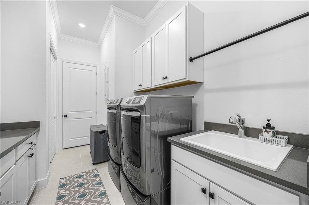 Laundry area with ornamental molding, light tile patterned floors, cabinet space, independent washer and dryer, and recessed lighting