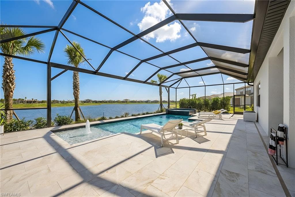 Integrated pool / hot tub with a sunroom, glass enclosure, a patio area, and a water view