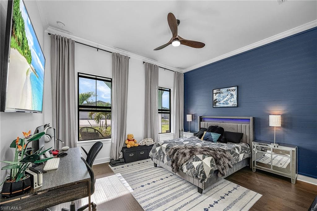 Bedroom with ornamental molding, wood finished floors, a ceiling fan, and an office area