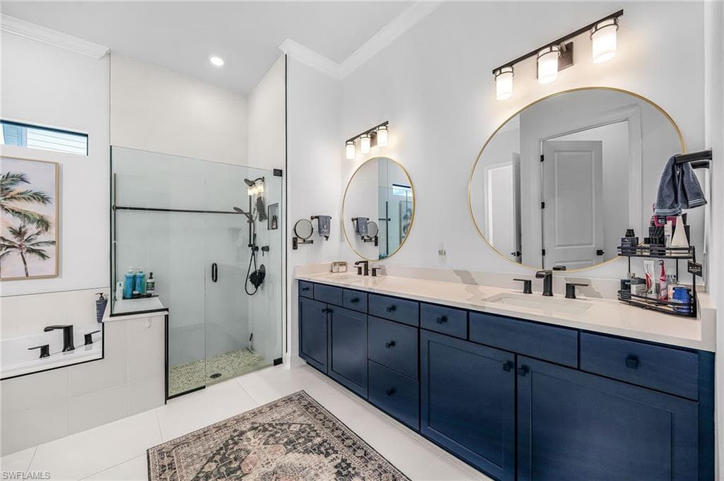Bathroom featuring double vanity, a stall shower, ornamental molding, light tile patterned floors, and recessed lighting
