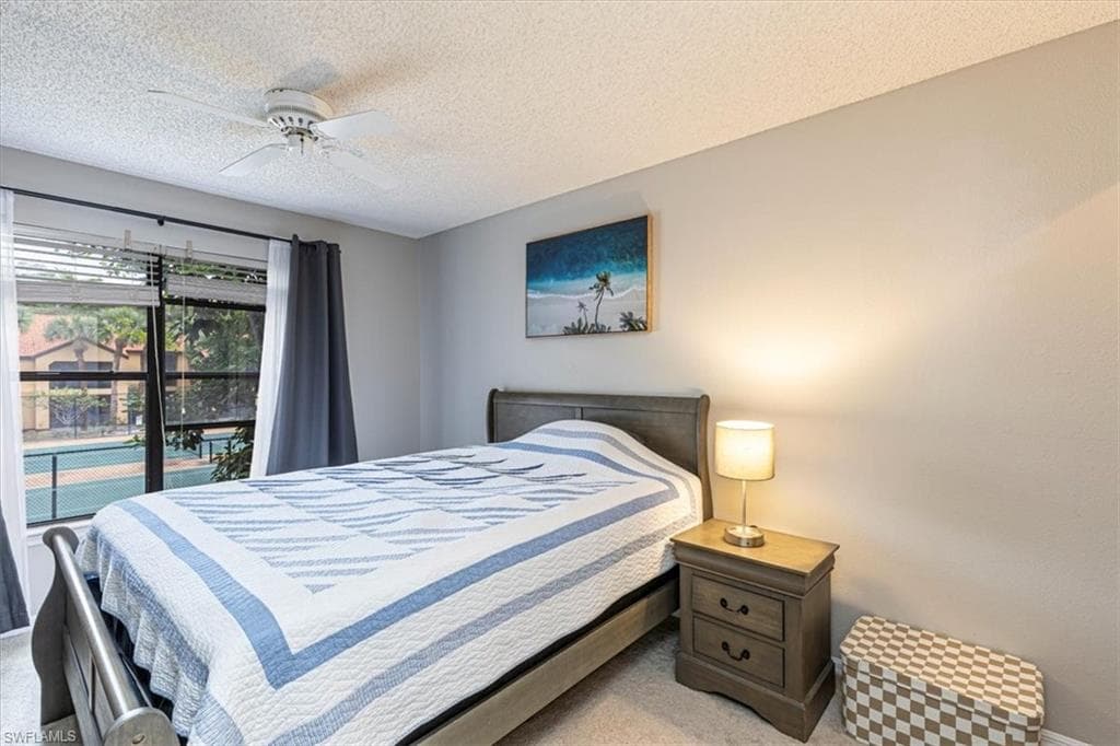 Carpeted bedroom featuring a ceiling fan, a textured ceiling, and access to outside