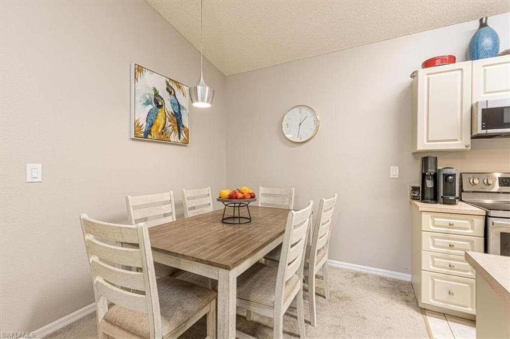 Dining area featuring light colored carpet and a textured ceiling