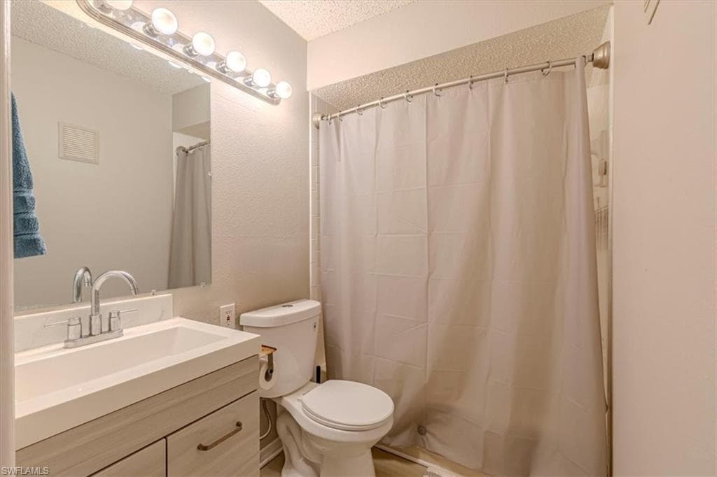 Full bathroom with vanity, a shower with shower curtain, and a textured ceiling