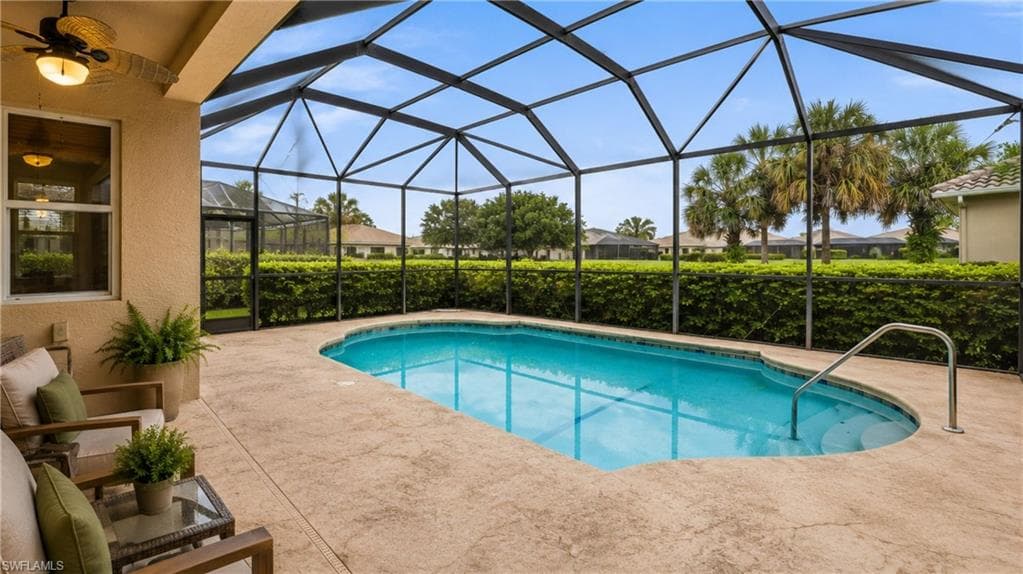 Screened-in outdoor pool featuring a textured concrete deck, integrated steps, and a handrail