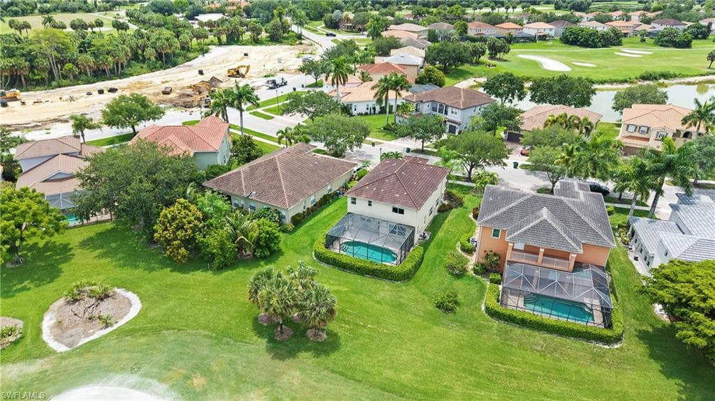 Aerial view showcasing a residential property with a screened swimming pool, surrounded by manicured landscaping and mature trees