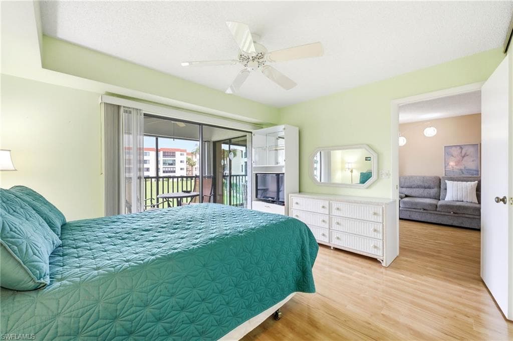 Bedroom with light wood-finish flooring, a ceiling fan, and direct access to a screened balcony