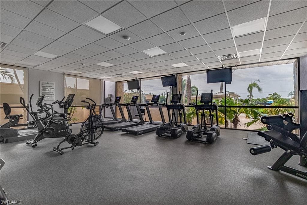 Fitness center featuring rubberized flooring, large windows, multiple cardio machines, strength training equipment, and mounted televisions