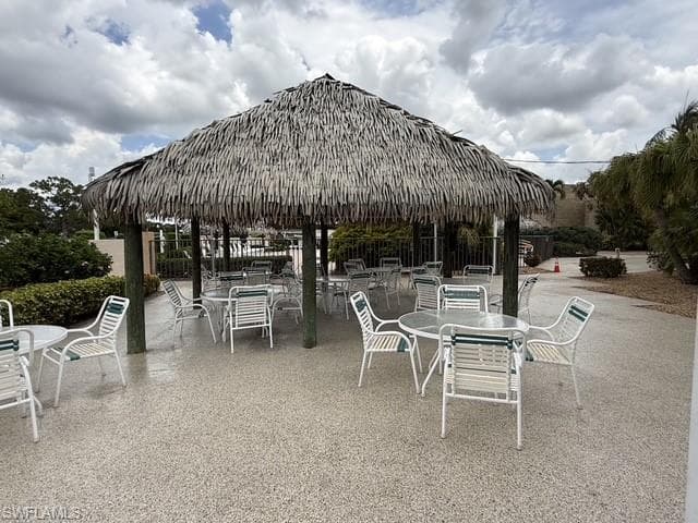 Thatch-roofed pergola with exposed wood support beams and a speckled aggregate concrete patio