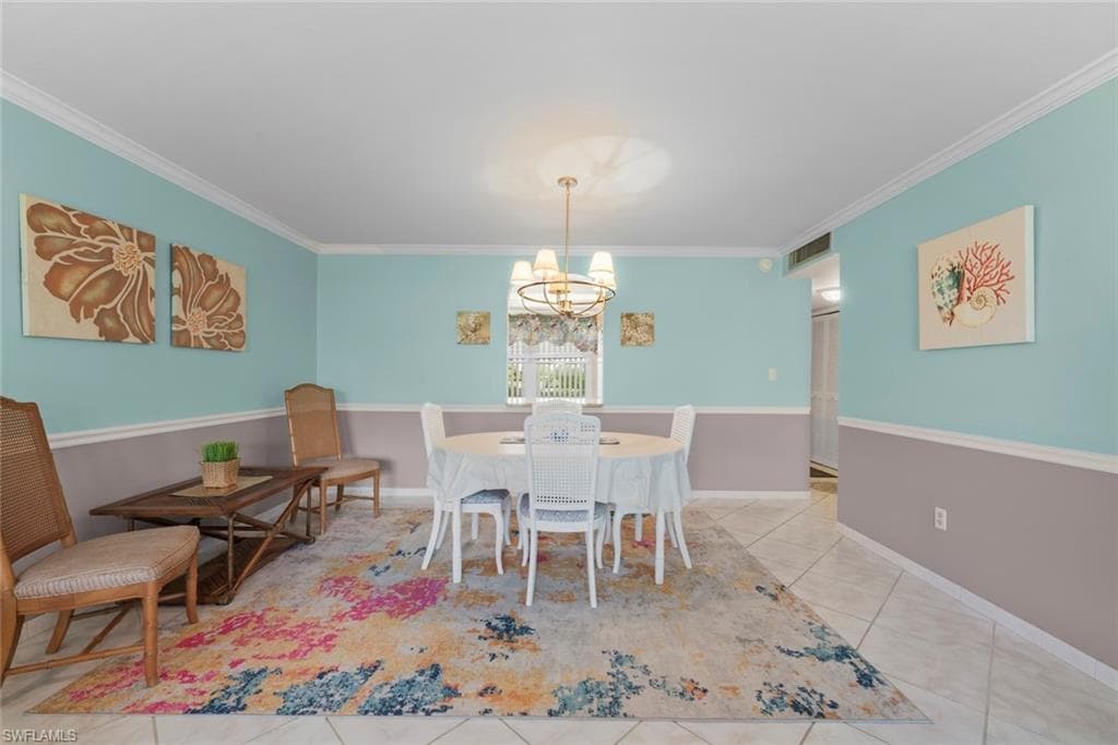Dining area featuring tile flooring, crown molding, and a chandelier lighting fixture