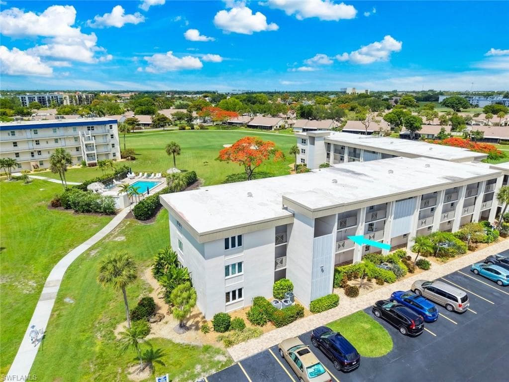 Aerial perspective showcasing the condo building with private balconies, one of the community's pool, and a few of the golf course