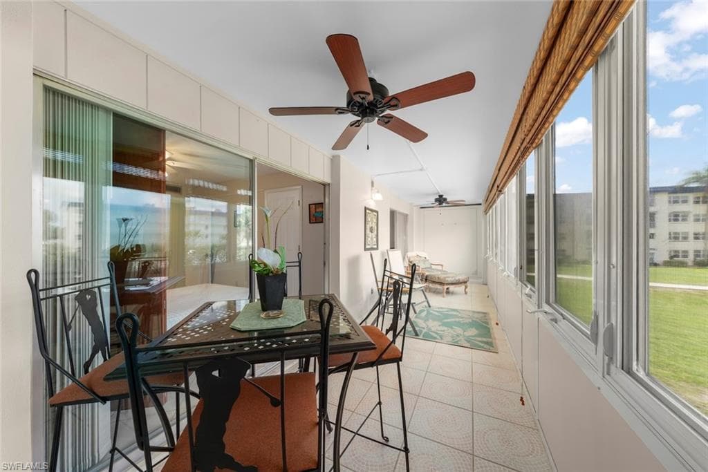 Enclosed sun room featuring windows, tile flooring, two ceiling fans, and sliding glass doors