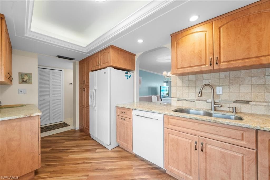 Kitchen featuring laminate flooring, light wood cabinetry, and a tile backsplash