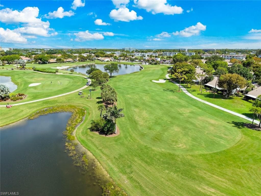 Expansive golf course setting featuring manicured greens, multiple water features, mature trees, and paved golf cart paths