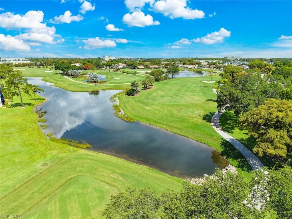 Expansive golf course landscape featuring meticulously manicured greens, mature trees, and a paved cart path
