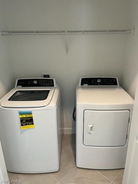 Washroom with washer and clothes dryer and light tile patterned floors
