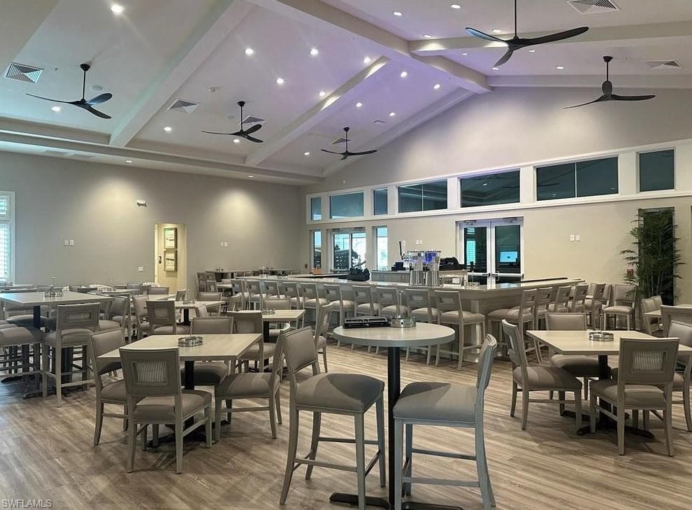 Dining space with a ceiling fan, high vaulted ceiling, beam ceiling, wood finished floors, and recessed lighting