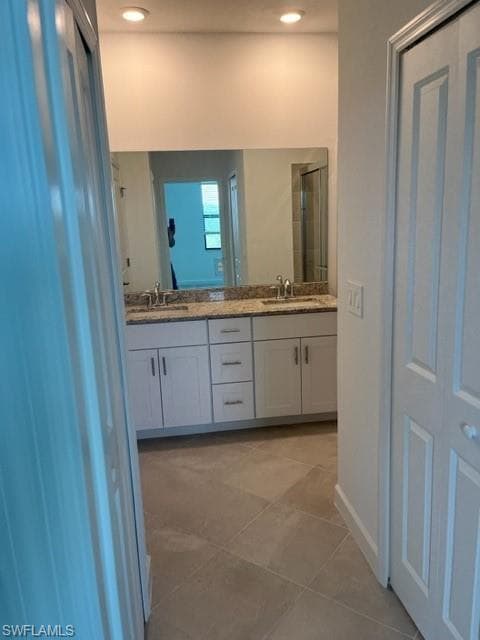 Bathroom with double vanity, tile patterned floors, an enclosed shower, baseboards, and recessed lighting