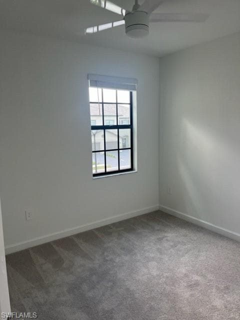 Carpeted empty room featuring a ceiling fan and baseboards