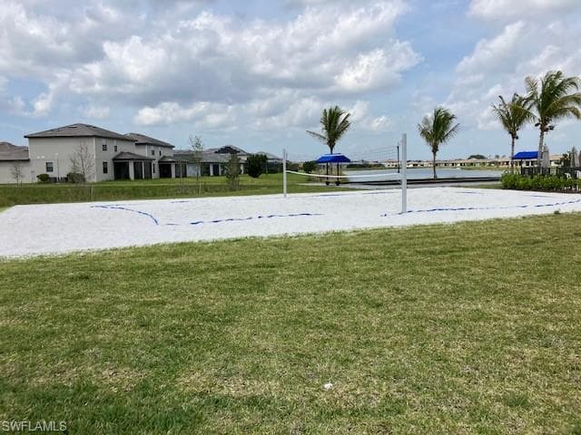 View of grassy yard featuring volleyball court and a water view