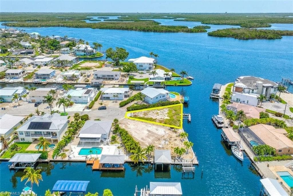 Waterfront property featuring clear canal access, surrounding residential development, and natural island vegetation in the distance - Virtually Edited Image