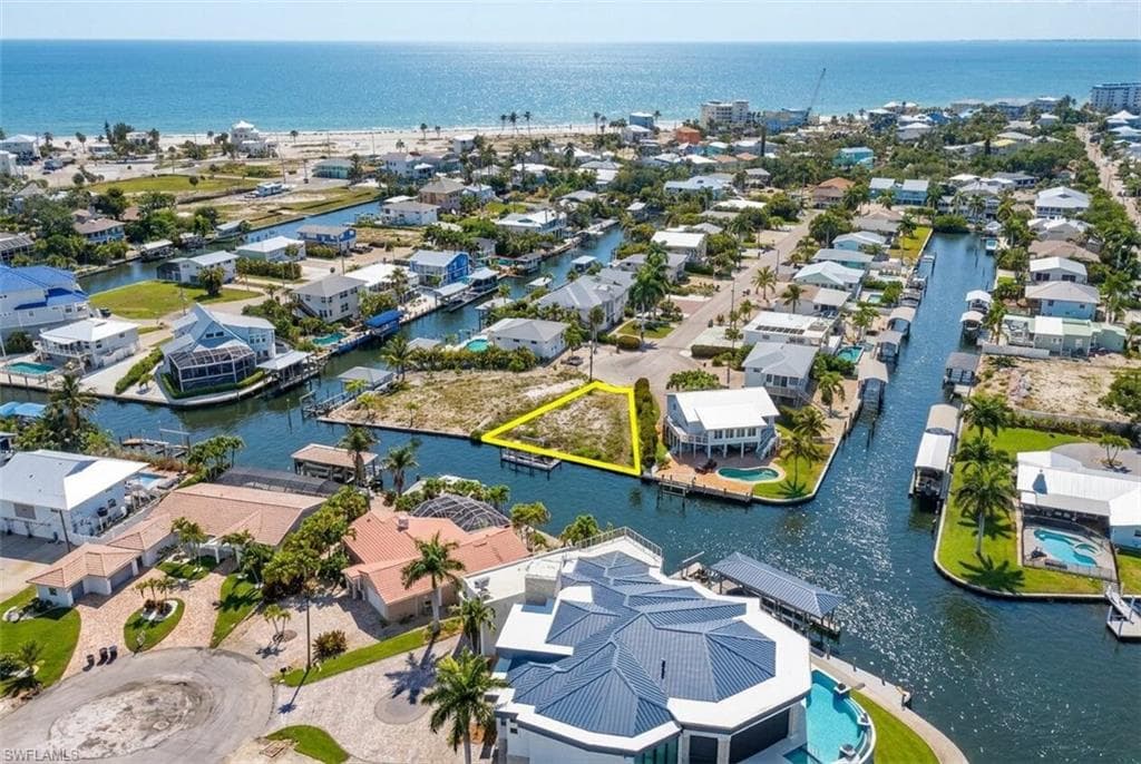 Waterfront lot featuring direct canal access, a defined perimeter, undeveloped land, and a boat dock structure - Virtually Edited Image