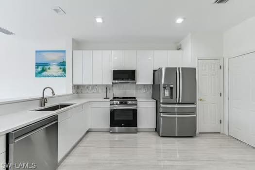 Kitchen featuring stainless steel appliances, white cabinetry, modern cabinets, and light countertops