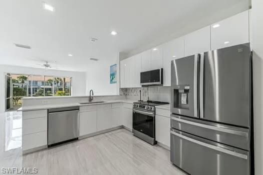 Kitchen featuring appliances with stainless steel finishes, modern cabinets, white cabinetry, light countertops, and recessed lighting