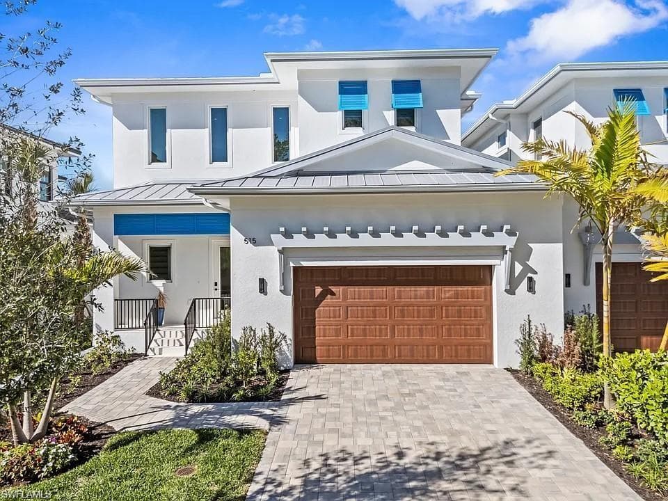 Contemporary residence featuring a white stucco exterior with a gray metal roof and blue architectural accents